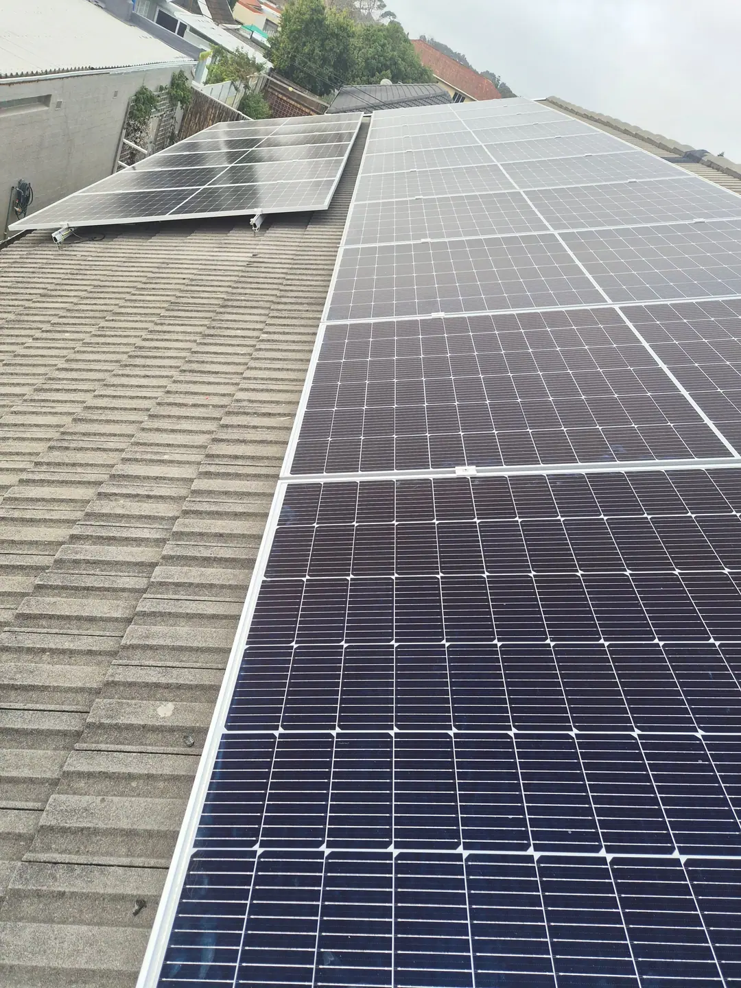 Close view of mono PV panels mounted on rails up a tiled roof